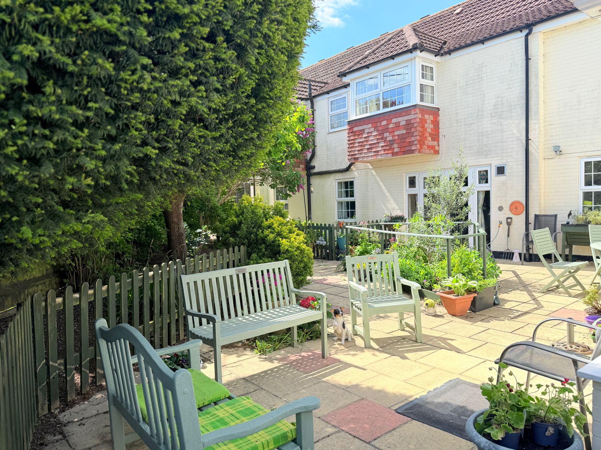 Care Services in Woodfalls Care Home viewed from its sunny courtyard with garden seating.