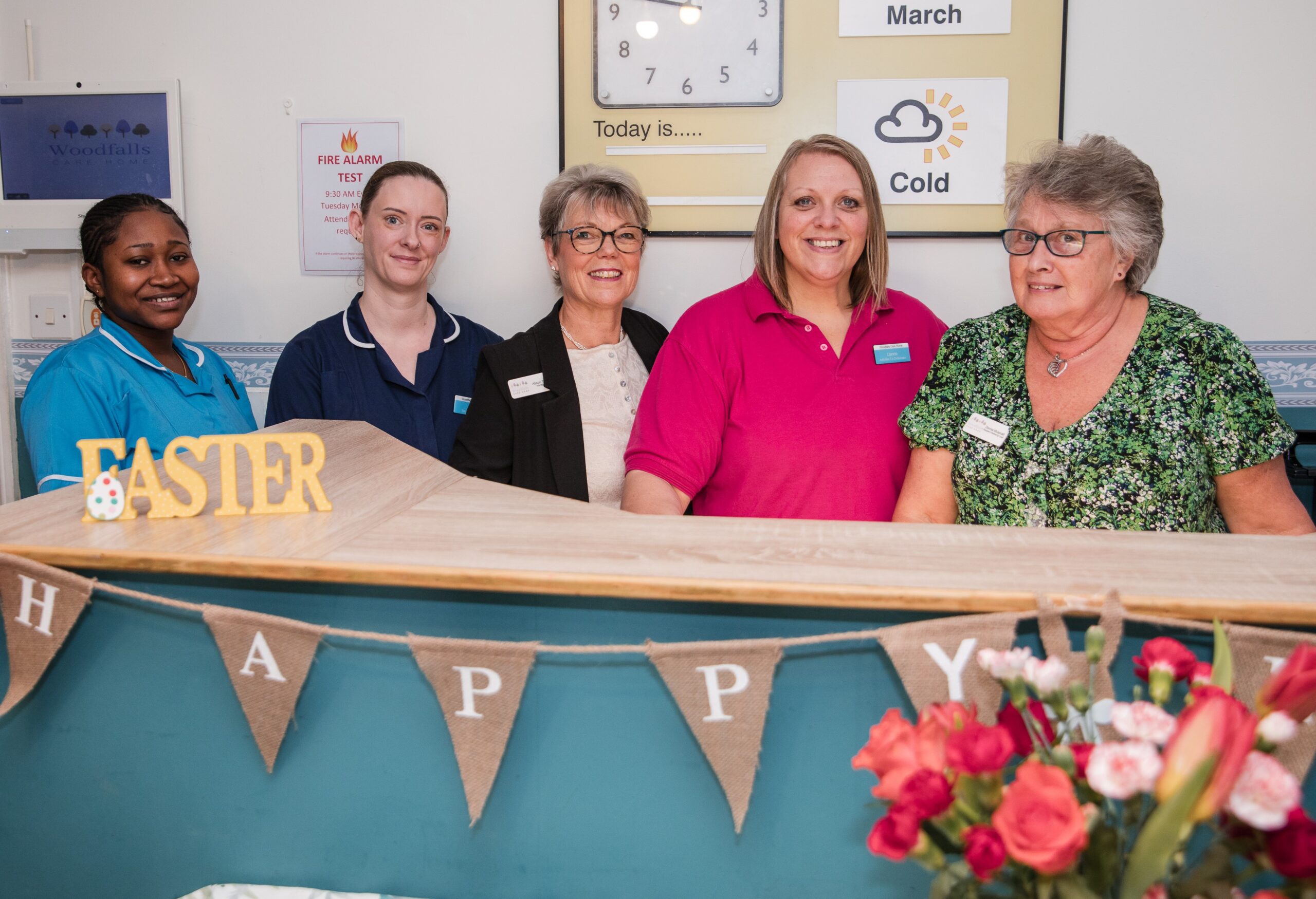 Woodfalls Care Home team members standing behind the reception desk with Easter decorations.